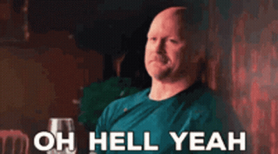 A Bald Man In A Blue Shirt Is Sitting At A Table With A Glass Of Wine And Says `` Oh Hell Yeah '' . GIF