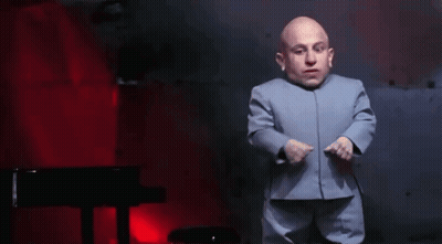 A Bald Man In A Blue Suit Is Dancing In Front Of A Piano . GIF