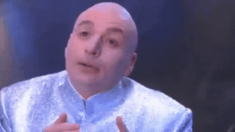 A Bald Man In A Blue Suit Is Making A Face . GIF