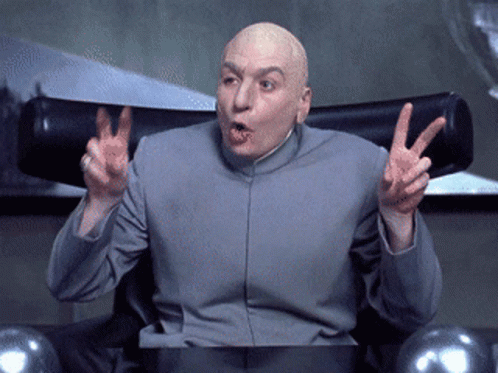 A Bald Man In A Gray Suit Is Giving A Peace Sign GIF