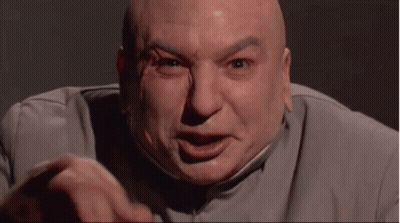 A Bald Man In A Gray Suit Is Making A Funny Face And Pointing At The Camera . GIF
