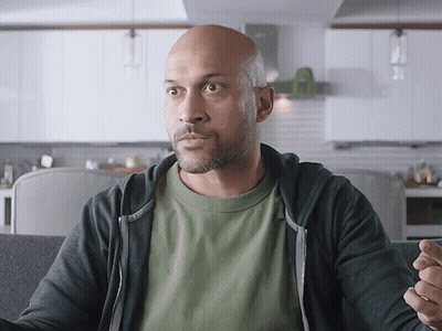 A Bald Man In A Green Shirt And Black Hoodie GIF