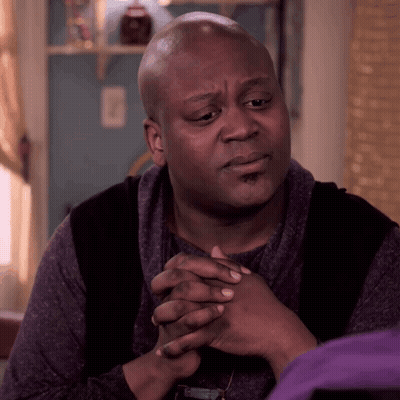 A Bald Man In A Purple Shirt Has His Hands Folded GIF