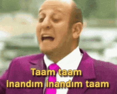 A Bald Man In A Purple Suit And Tie Says Taam Taam Inandim Inandim Taam GIF