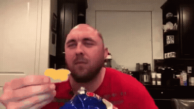 A Bald Man In A Red Shirt Eating A Bag Of Chips GIF