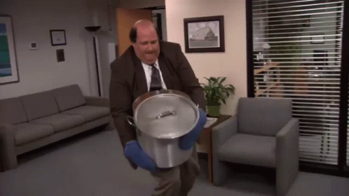 A Bald Man In A Suit And Tie Is Carrying A Pot GIF