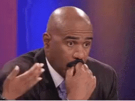A Bald Man In A Suit And Tie Is Covering His Mouth With His Hands . GIF