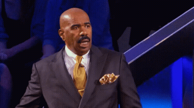 A Bald Man In A Suit And Tie Is Sitting In Front Of A Blue Background GIF
