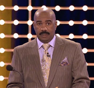 A Bald Man In A Suit And Tie Is Speaking Into A Microphone GIF