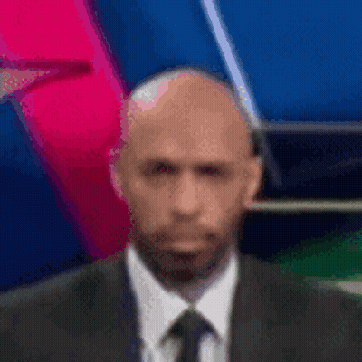 A Bald Man In A Suit And Tie Is Standing In Front Of A Colorful Background . GIF