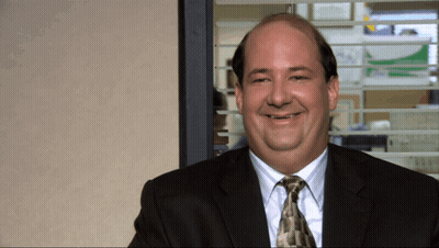 A Bald Man In A Suit And Tie Smiles In Front Of A Window GIF