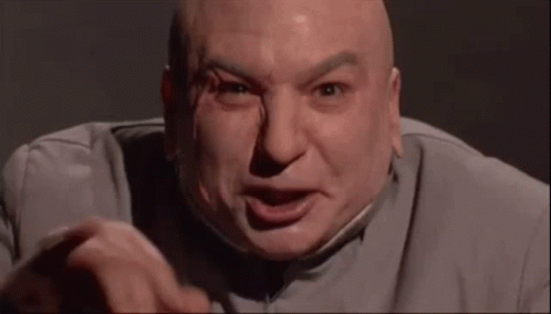 A Bald Man In A Suit Is Making A Funny Face And Pointing At The Camera . GIF