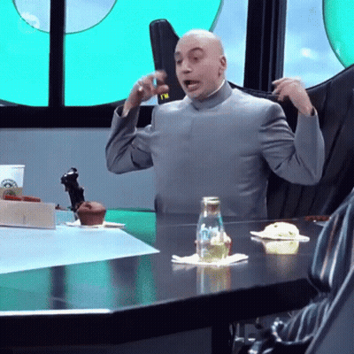 A Bald Man In A Suit Is Sitting At A Table With A Bottle Of Water On It GIF