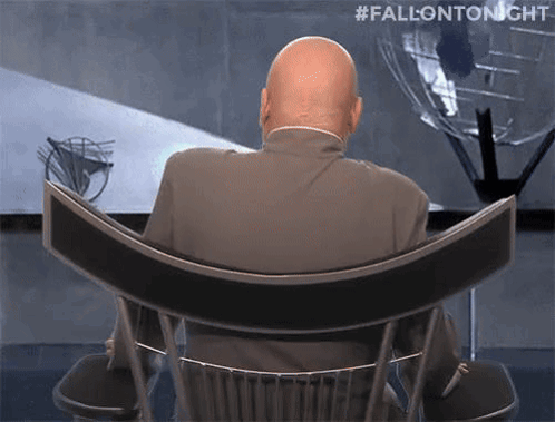 A Bald Man In A Suit Is Sitting In A Chair With His Back To The Camera And #Fallontonight Written Above Him . GIF