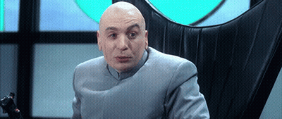 A Bald Man In A Suit Sits In A Black Chair GIF