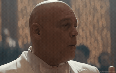 a bald man in a white tuxedo and bow tie is talking