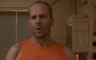 A Bald Man In An Orange Tank Top Is Standing In Front Of A Sign That Says I Am Not Going GIF