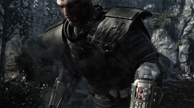 A Bald Man In Armor Stands In Front Of A Rocky Cliff GIF