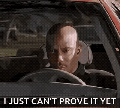 A Bald Man Is Driving A Car With The Words `` I Just Can 'T Prove It Yet '' Written On The Steering Wheel . GIF
