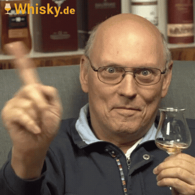 A Bald Man Is Holding A Glass Of Whisky And Giving A Thumbs Up Sign GIF