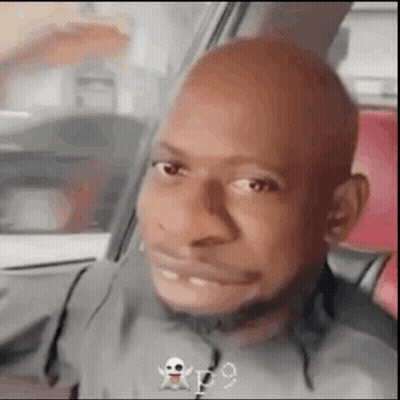 A Bald Man Is Making A Funny Face While Sitting In The Back Seat Of A Car . GIF