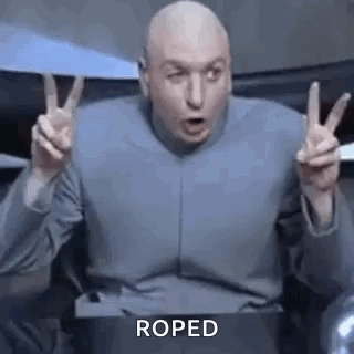 A Bald Man Is Making A Peace Sign With His Hands While Sitting In A Chair . GIF