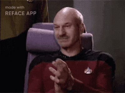 A Bald Man Is Sitting In A Chair Clapping His Hands In A Movie Theater . GIF