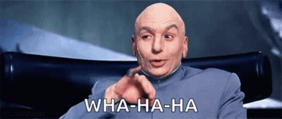 A Bald Man Is Sitting In A Chair Making A Funny Face And Pointing At The Camera . GIF