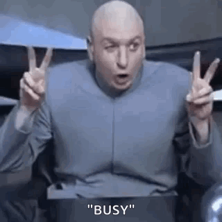 A Bald Man Is Sitting In A Chair Making A Peace Sign . GIF