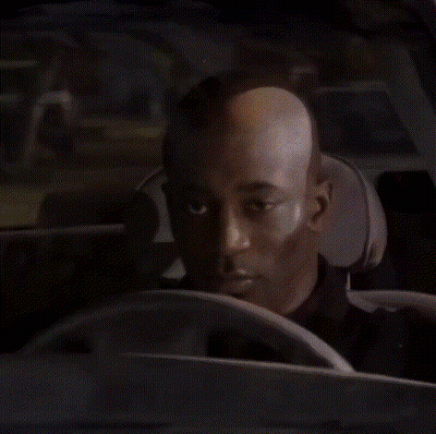 A Bald Man Is Sitting In The Driver 'S Seat Of A Car . GIF