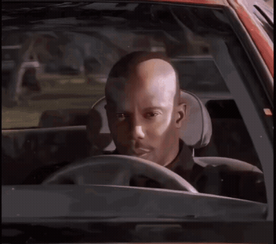 A Bald Man Is Sitting In The Driver 'S Seat Of A Car Looking At The Camera . GIF