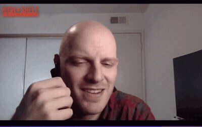A Bald Man Is Smiling In Front Of A Screen That Says High Shelf Interactive GIF