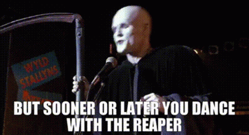 A Bald Man Is Standing In Front Of A Microphone With The Words But Sooner Or Later You Dance With The Reaper Above Him . GIF