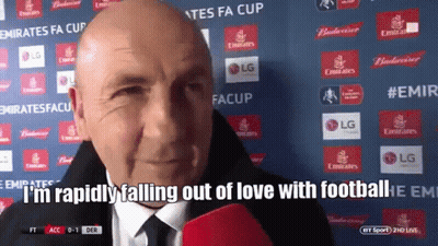 A Bald Man Is Talking Into A Microphone With The Words " I 'M Rapidly Falling Out Of Love With Football " Behind Him GIF