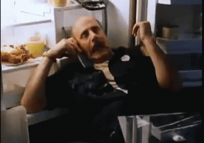A Bald Man Is Talking On A Cell Phone In A Refrigerator . GIF