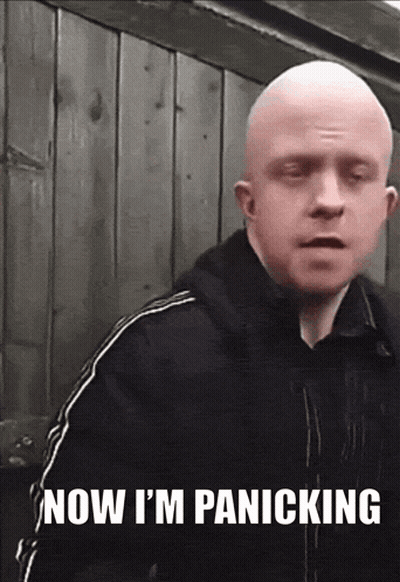 A Bald Man Says " Now I 'M Panicking " In Front Of A Wooden Wall GIF