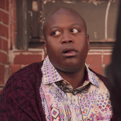 A Bald Man Wearing A Colorful Shirt And A Purple Cardigan Looks Surprised GIF