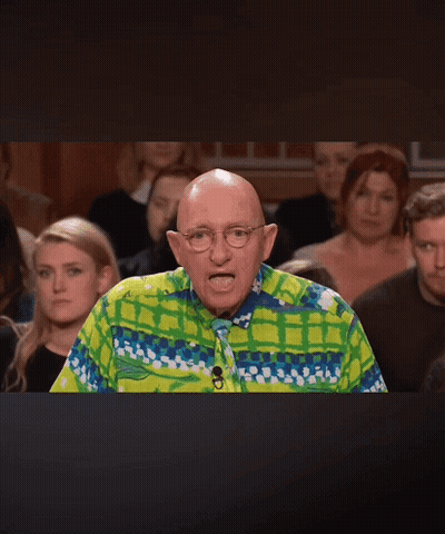 A Bald Man Wearing A Colorful Shirt And Tie Stands In Front Of A Crowd Of People GIF