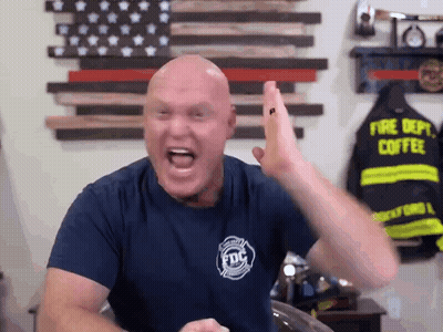A Bald Man Wearing A Fire Dept Coffee Shirt Is Giving A High Five GIF