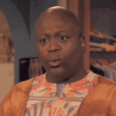 A Bald Man Wearing A Floral Shirt And A Cardigan Is Making A Funny Face . GIF