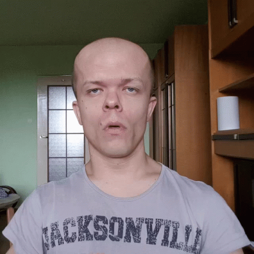 A Bald Man Wearing A Jacksonville T-Shirt Looks At The Camera GIF