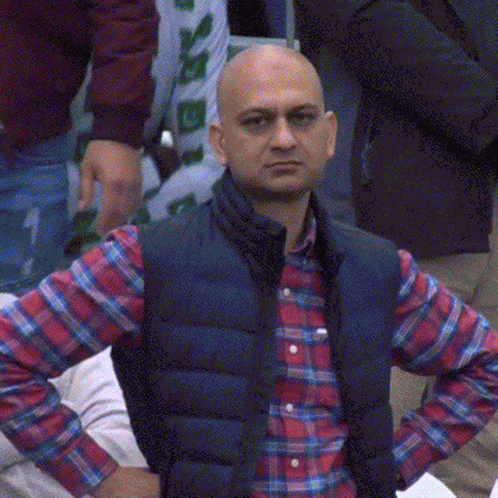 A Bald Man Wearing A Plaid Shirt And A Black Vest GIF