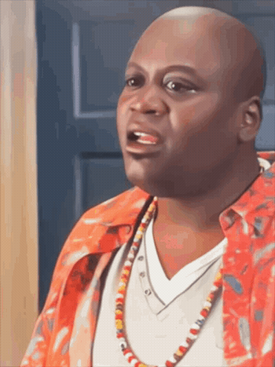 A Bald Man Wearing A Red Shirt And A Necklace Is Talking GIF