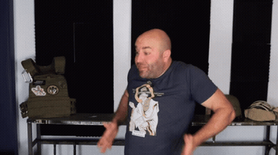 A Bald Man Wearing A T-Shirt With A Picture Of A Man Holding A Gun GIF