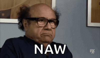 A Bald Man Wearing Glasses And A Black Shirt Is Sitting In Front Of A Wall And Saying Naw . GIF