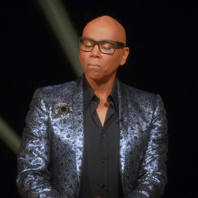 A Bald Man Wearing Glasses And A Blue Jacket Looks Down GIF