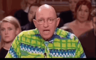 A Bald Man Wearing Glasses And A Colorful Shirt Is Standing In Front Of A Crowd . GIF