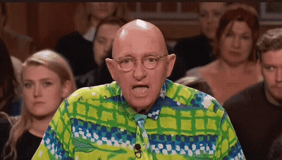 A Bald Man Wearing Glasses And A Colorful Shirt Stands In Front Of A Crowd . GIF
