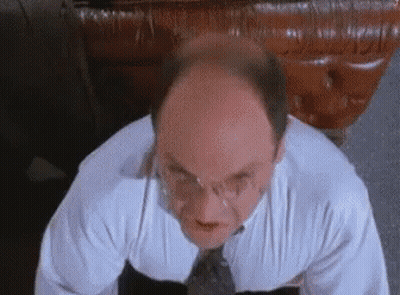 A Bald Man Wearing Glasses And A White Shirt And Tie Is Looking Up At The Camera . GIF