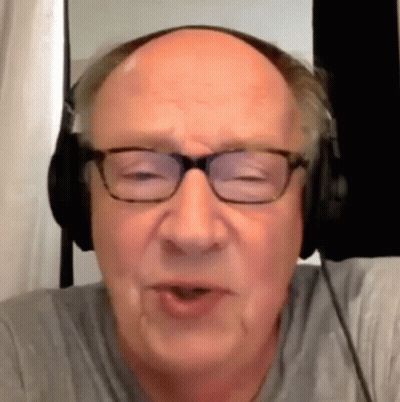 A Bald Man Wearing Glasses And Headphones Is Talking To Someone . GIF